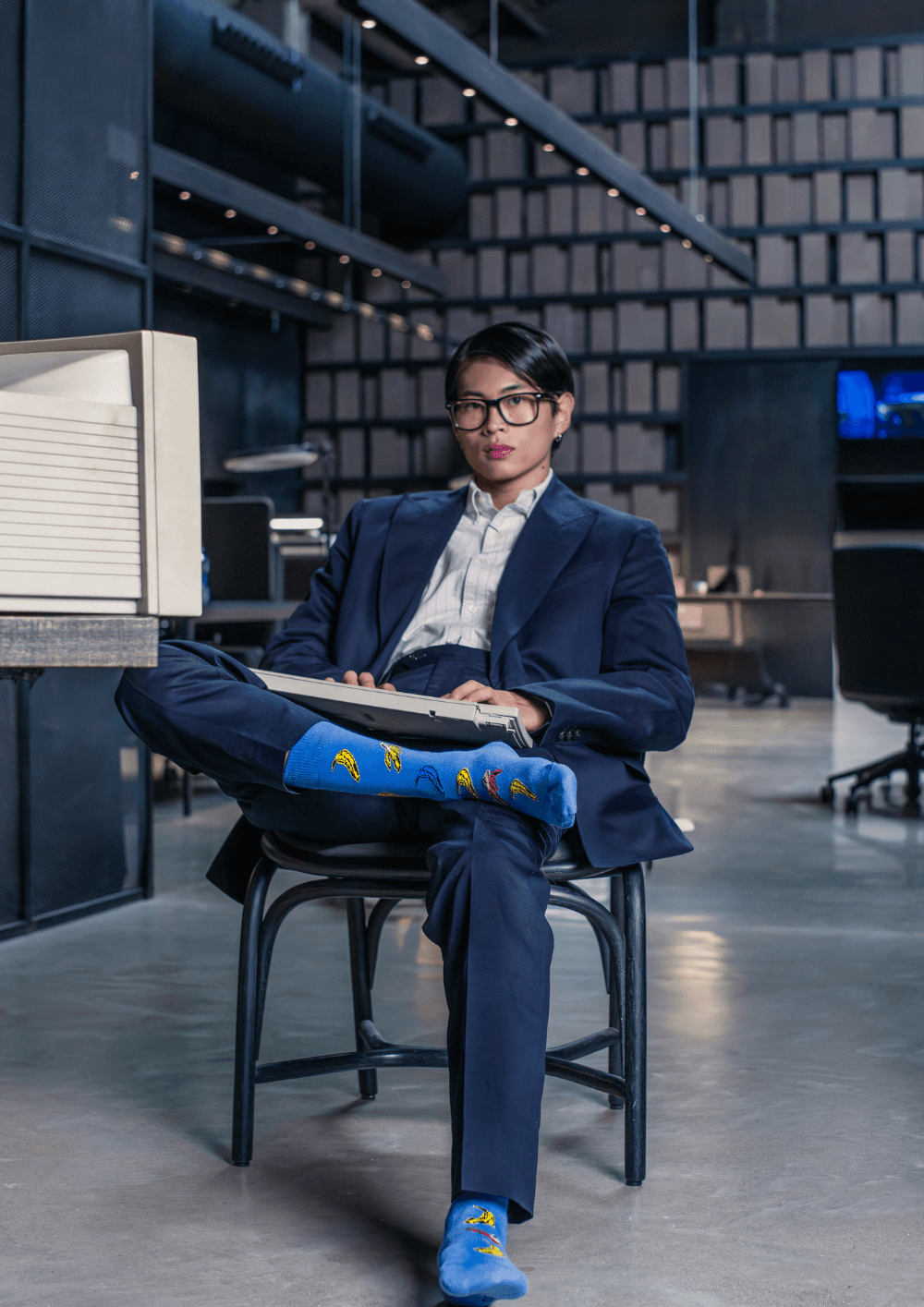 Si sigues haciendo esto, tus looks de oficina siempre se verán aburridos. Hombre con traje y calcetines llamativos en oficina moderna.