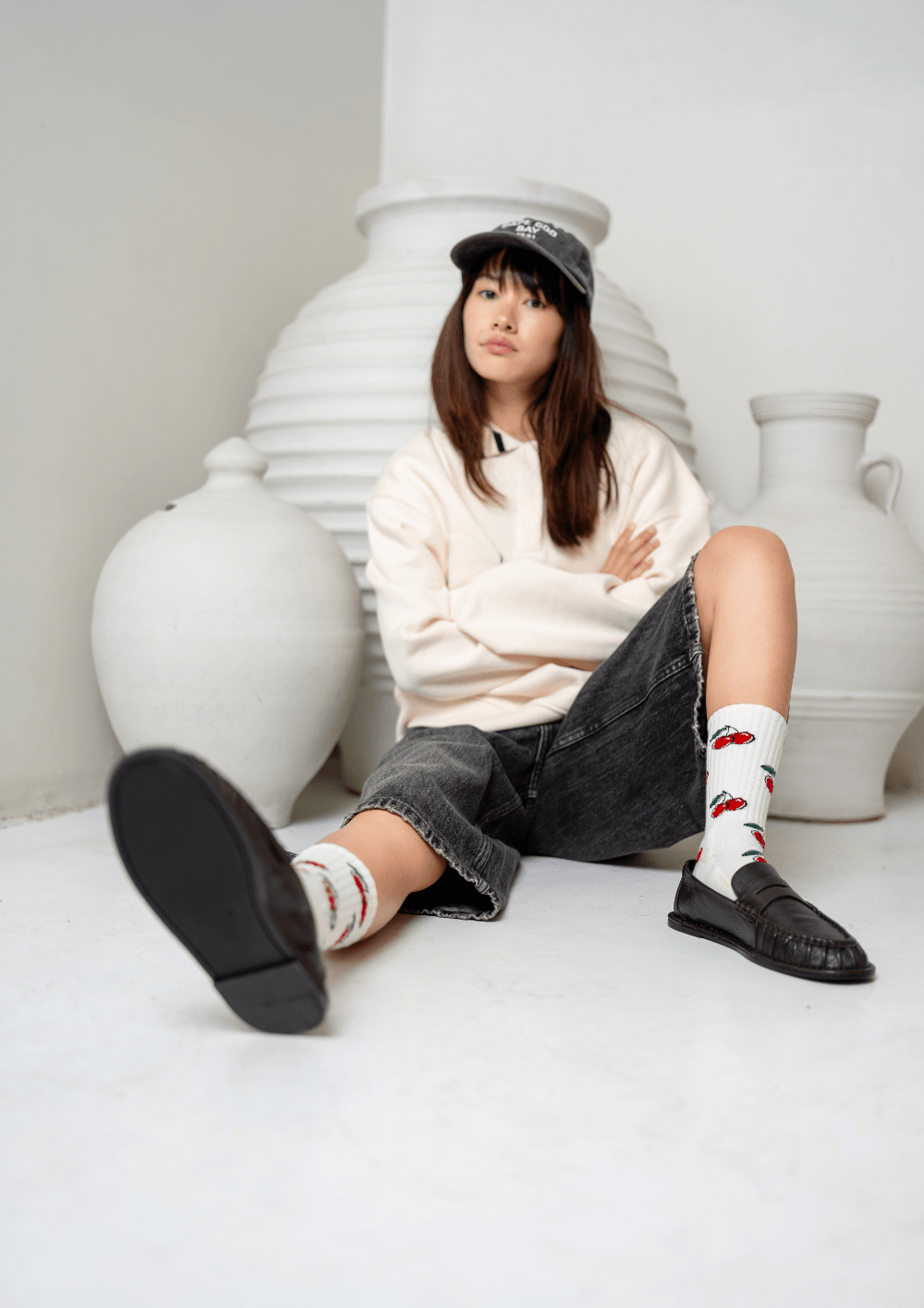 Mujer sentada en el suelo con calcetines y mocasines, luciendo un estilo urbano contemporáneo.