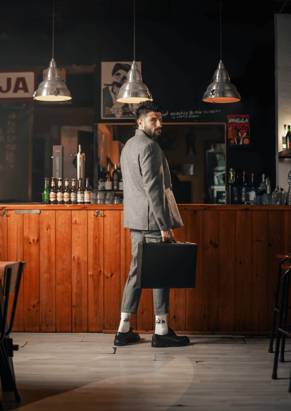 Cómo combinar calcetines con traje y lograr un look impecable, hombre en traje gris con maletín y calcetines elegantes.
