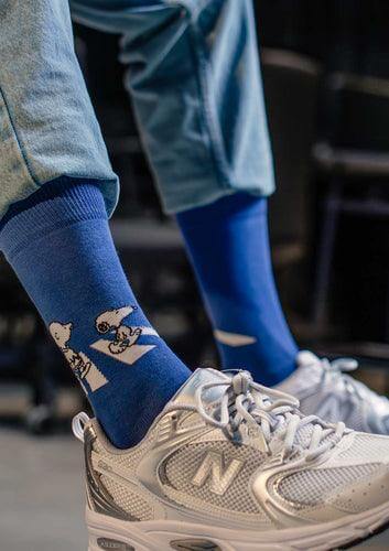 Como combinar calcetines con sneakers: calcetines azules con diseño de Snoopy y zapatillas New Balance.