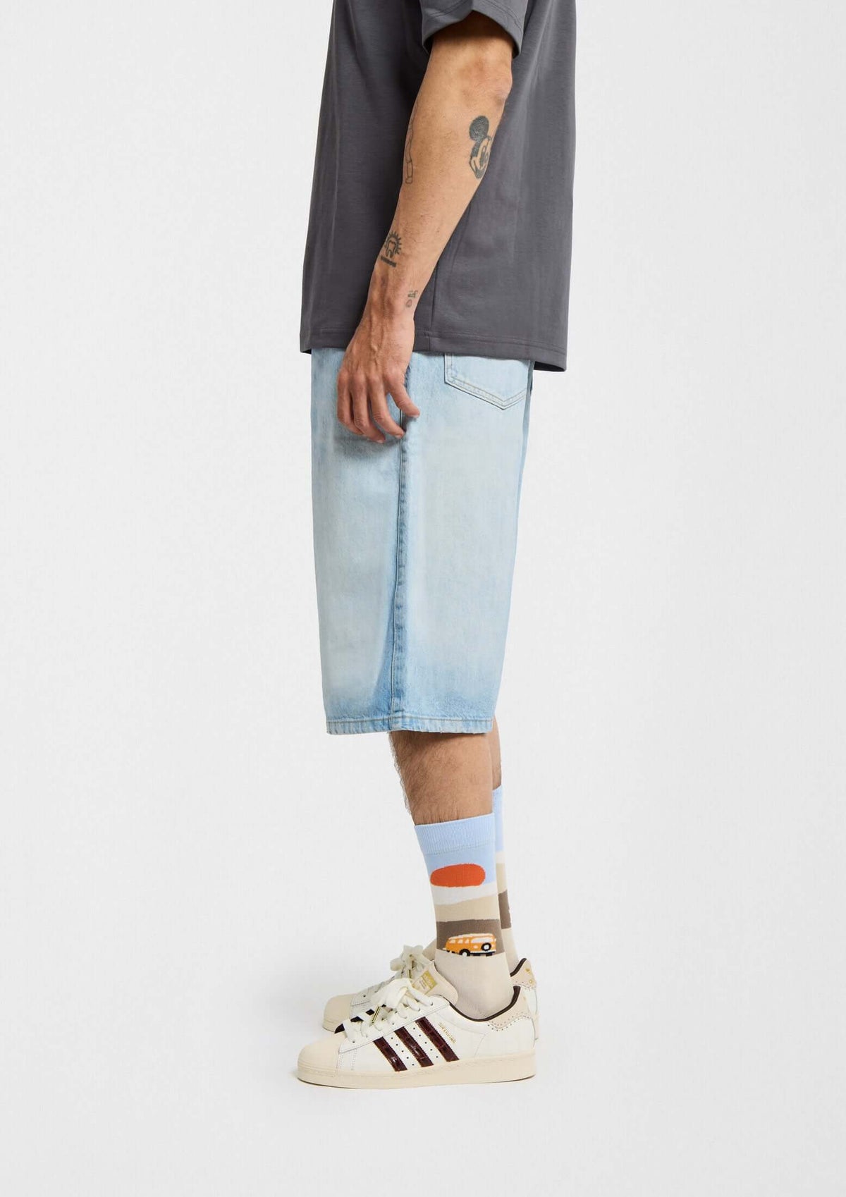 Modelo usando calcetines originales BeRoadTrip con dibujo de desierto y furgoneta amarilla, combinados con shorts de mezclilla.