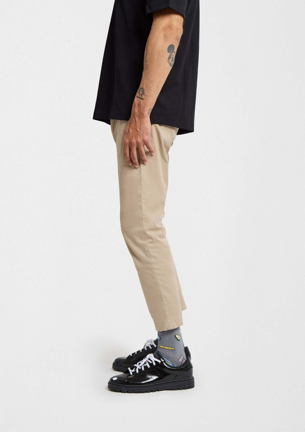 Hombre de perfil con calcetines BeBrunch Grey, pantalones color arena y zapatillas negras. Look moderno y original.