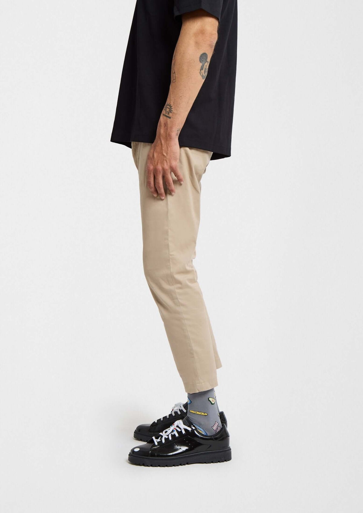 Hombre de perfil con calcetines BeBrunch Grey, pantalones color arena y zapatillas negras. Look moderno y original.