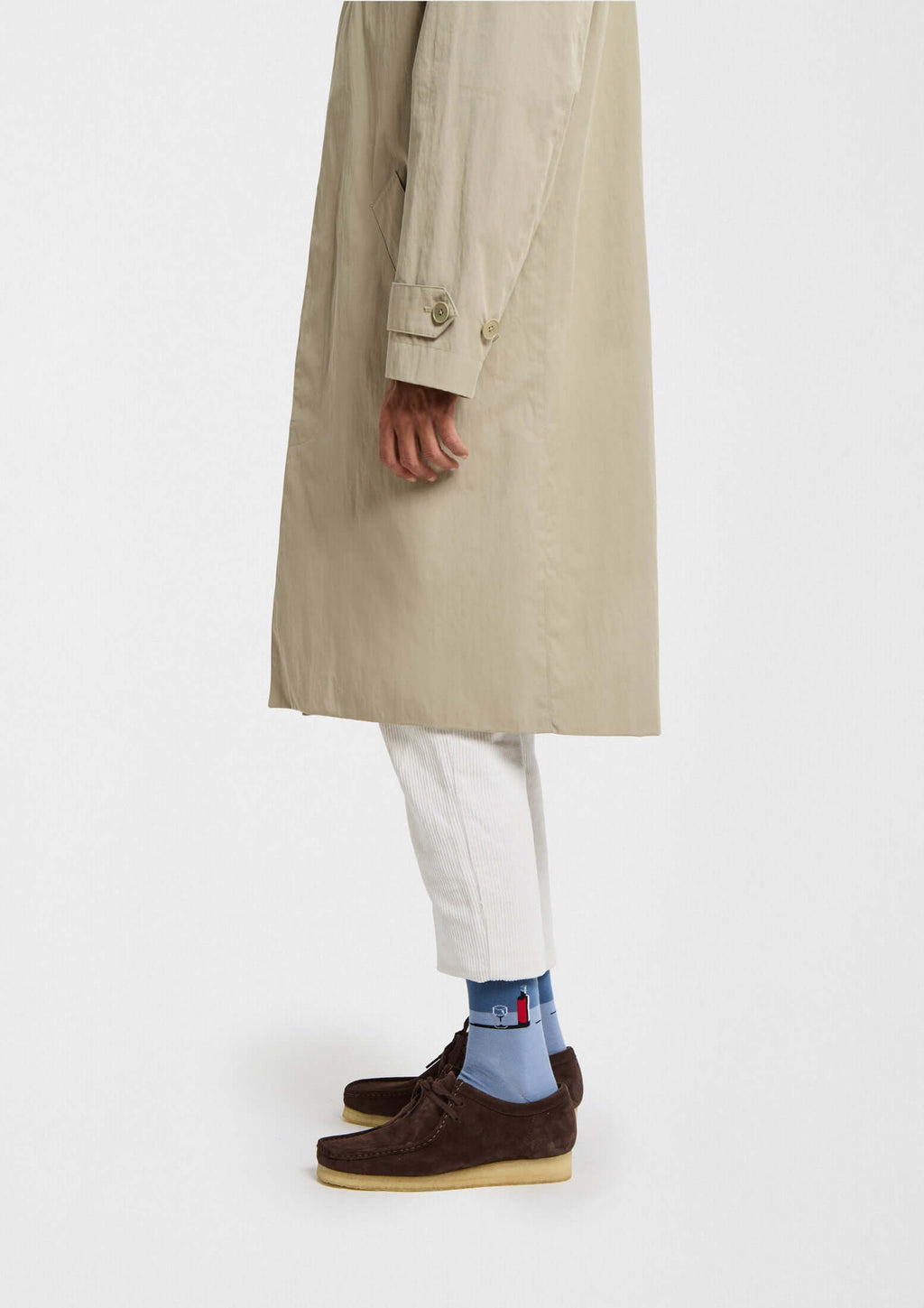 Modelo vistiendo abrigo beige y zapatos oscuros, mostrando calcetines originales BeWine en tonos azules.