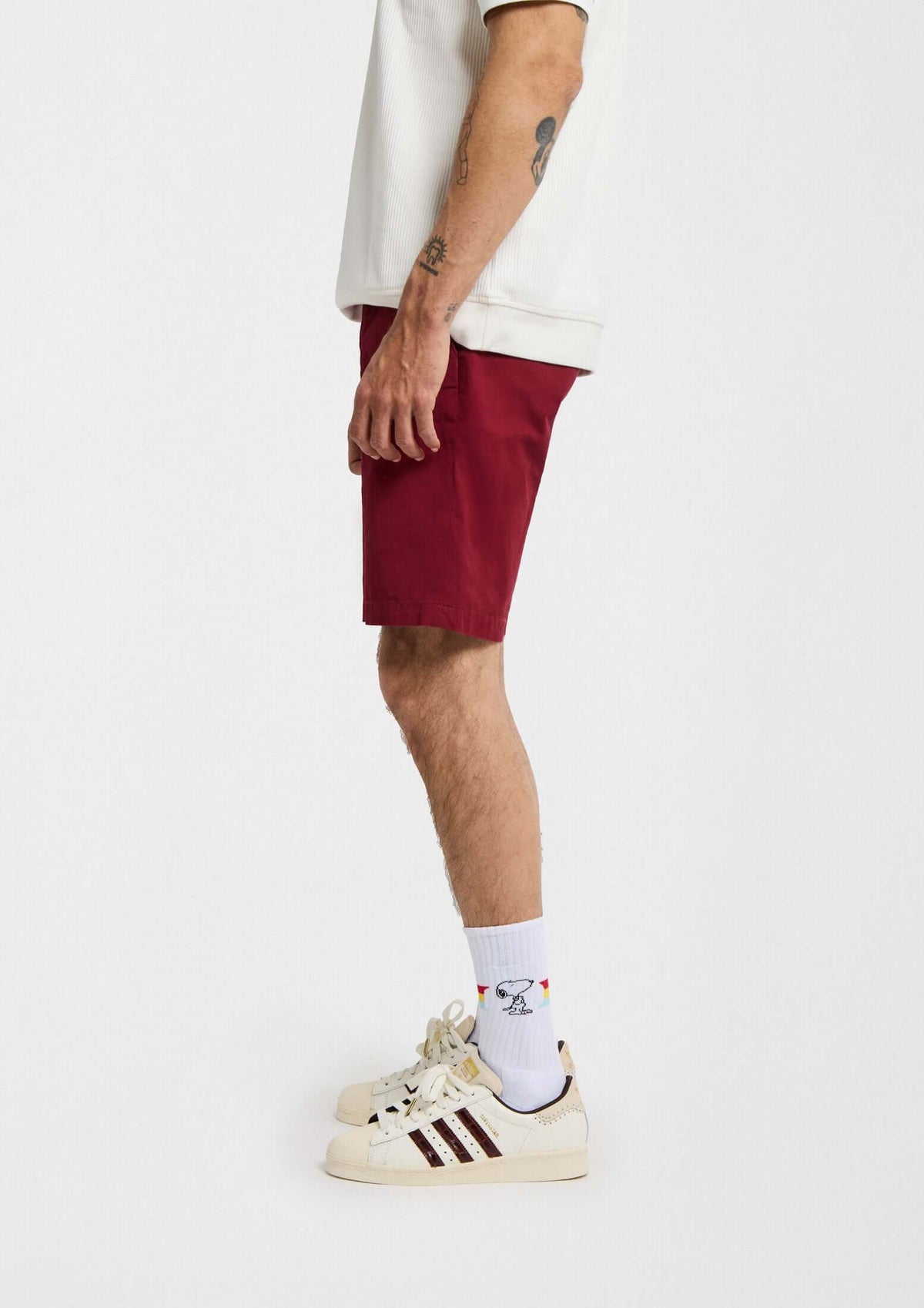 BeSnoopy Rainbow, calcetines altos con dibujos de Snoopy y banda arcoíris sobre fondo blanco, combinados con shorts rojos.
