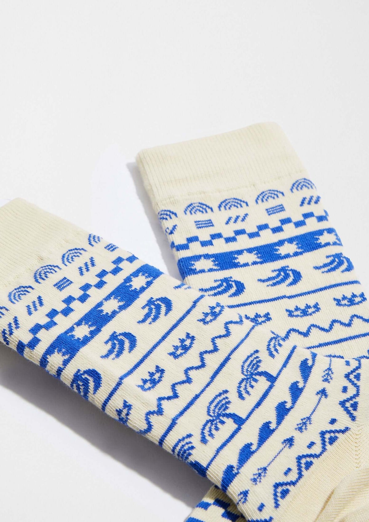 BeMosaic calcetines originales con dibujos geométricos y tropicales en azul sobre fondo beige claro.