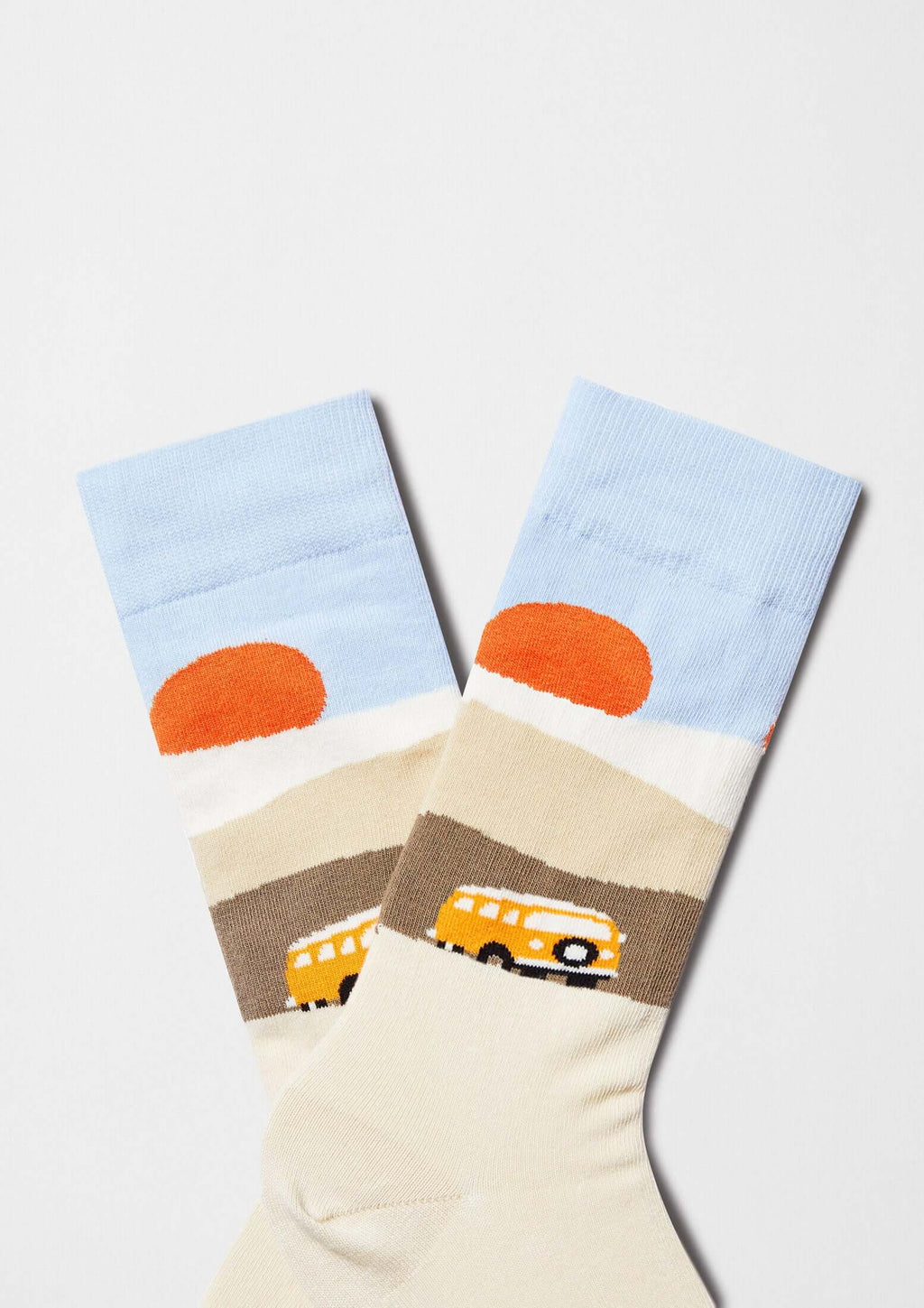 Calcetines originales BeRoadTrip con diseño de furgoneta amarilla y escena de carretera en tonos beige y azul.