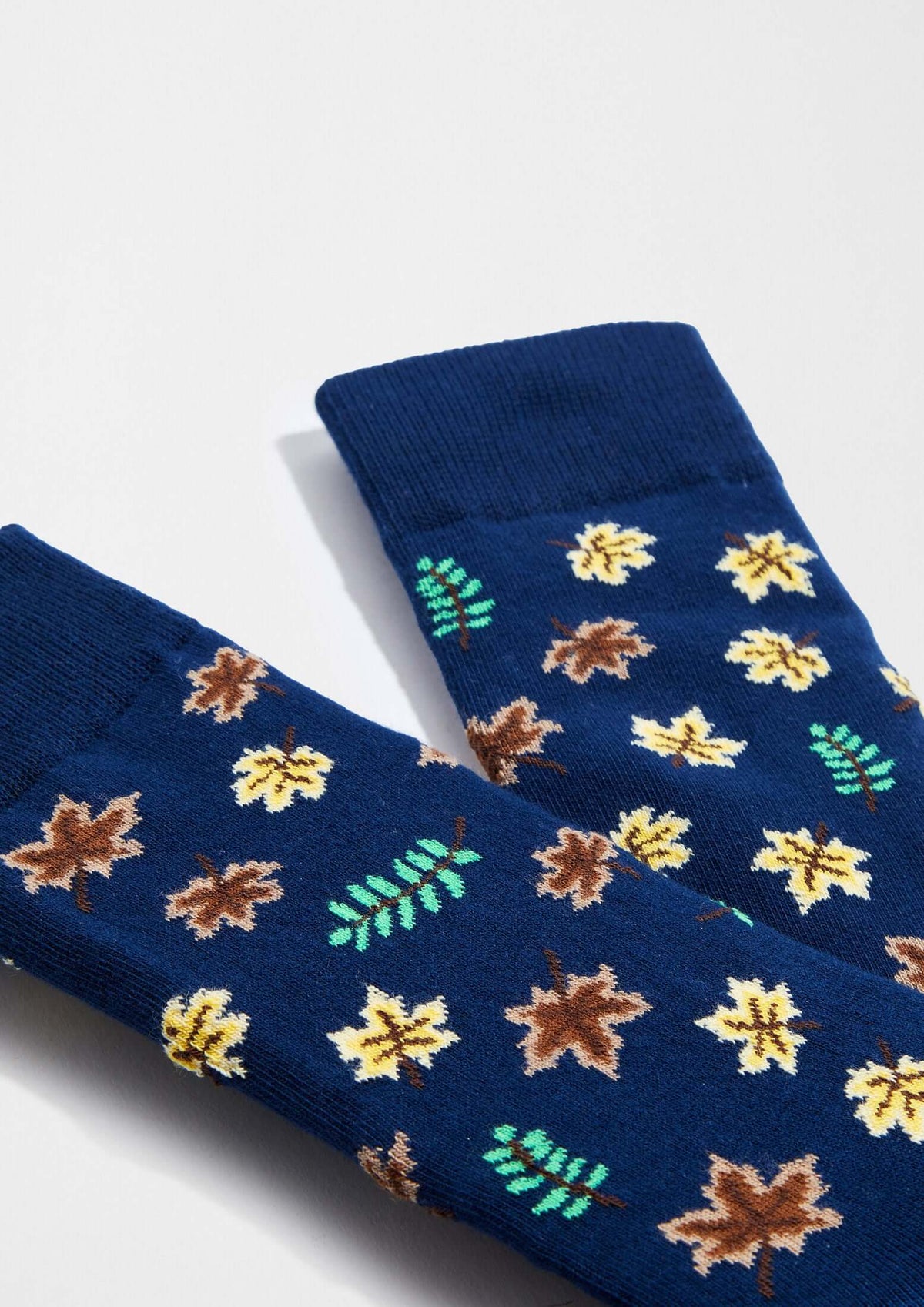 Calcetines originales BeAutumn con dibujos de hojas en tonos marrones, amarillos y verdes sobre fondo azul marino.