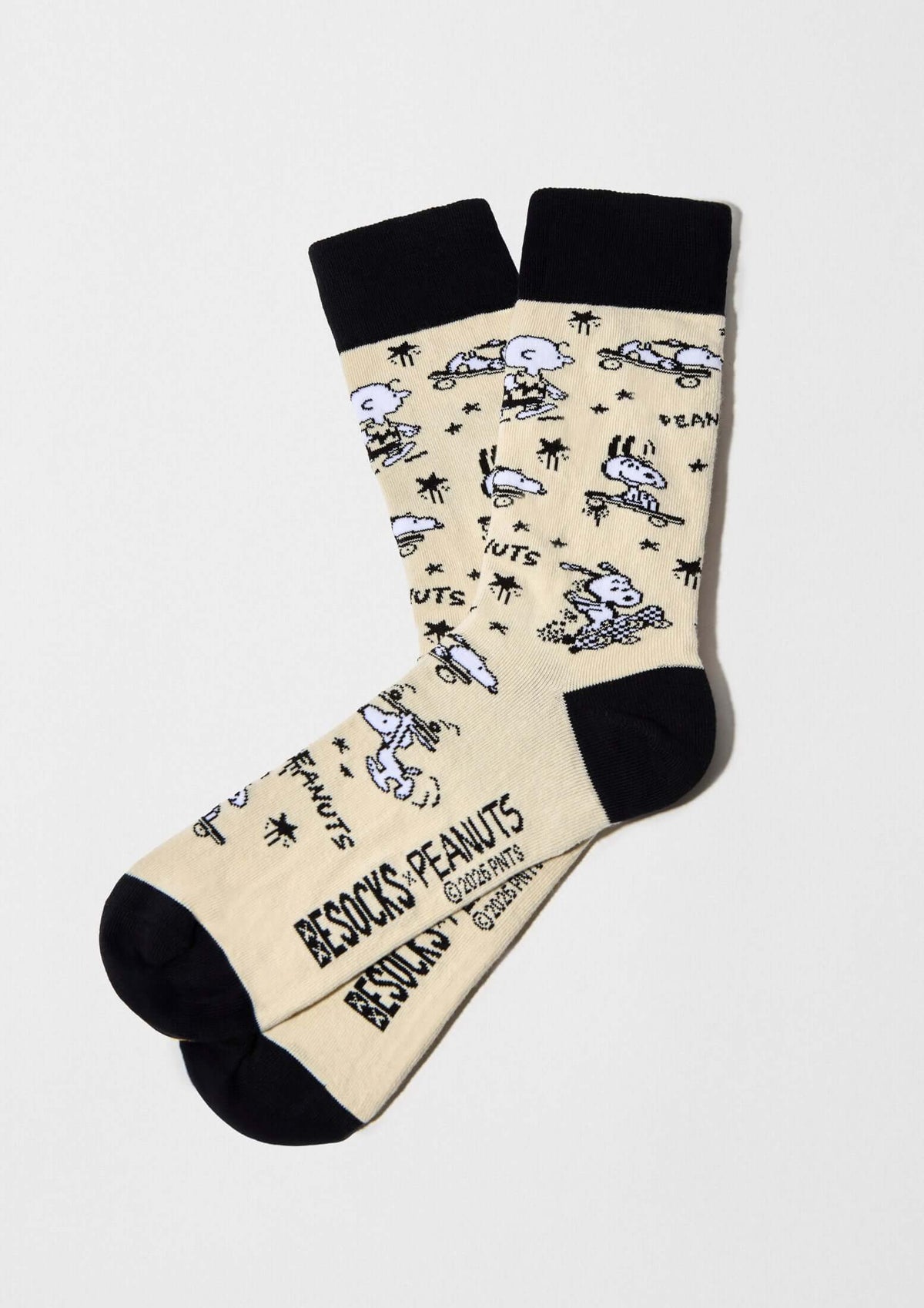Calcetines altos BeSnoopy Skate Beige con dibujos de Snoopy y Charlie Brown sobre fondo beige y detalles en negro.