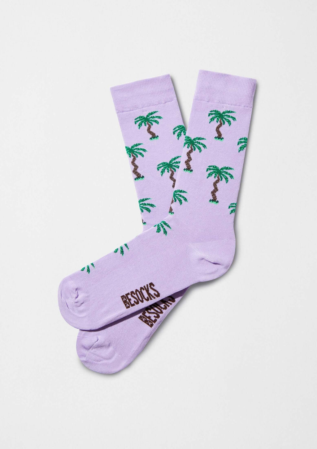 Calcetines originales BePalm con dibujos de palmeras verdes sobre fondo lila, logotipo de BESOCKS en marrón.