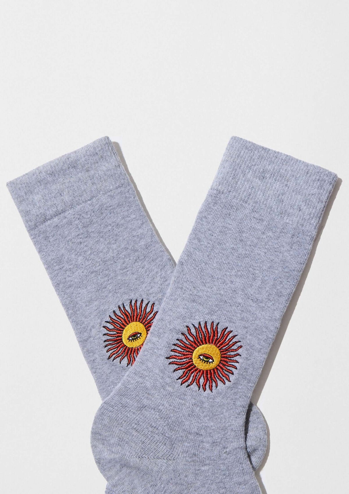 Calcetines BeSun Embroidered en gris con bordado de sol en hilo rojo y amarillo, ideales para looks casuales.