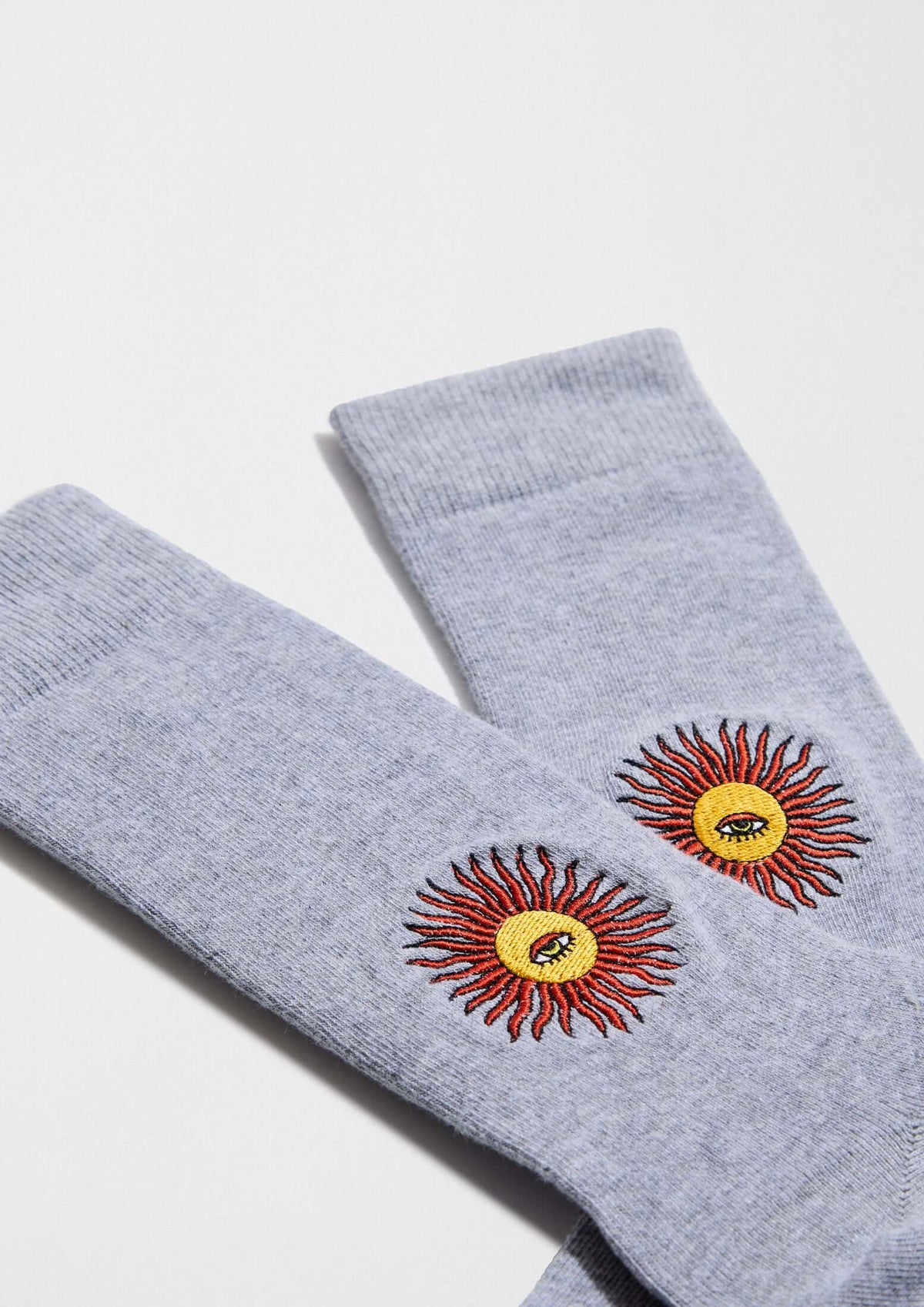 Calcetines BeSun Embroidered en gris con bordado de sol en hilo rojo y amarillo, perfectos para looks casuales.
