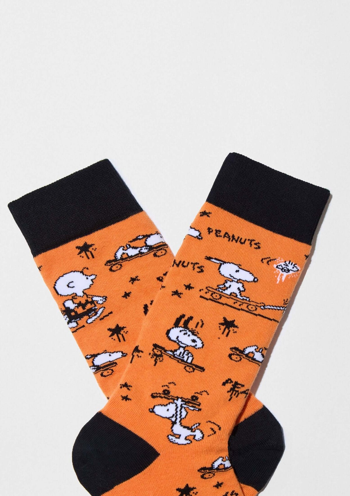Calcetines altos BeSnoopy Skate Orange de algodón orgánico con dibujos de Snoopy y Charlie Brown sobre fondo naranja.