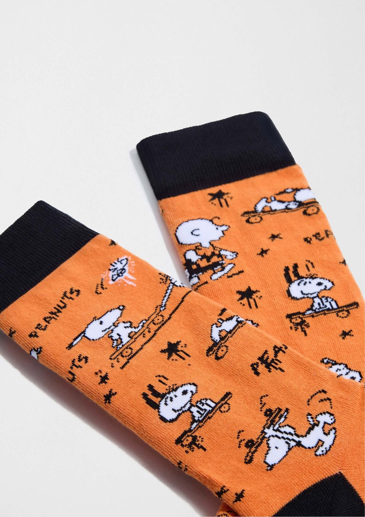 Calcetines altos BeSnoopy Skate Orange con dibujos de Snoopy y Charlie Brown sobre fondo naranja y detalles en negro.
