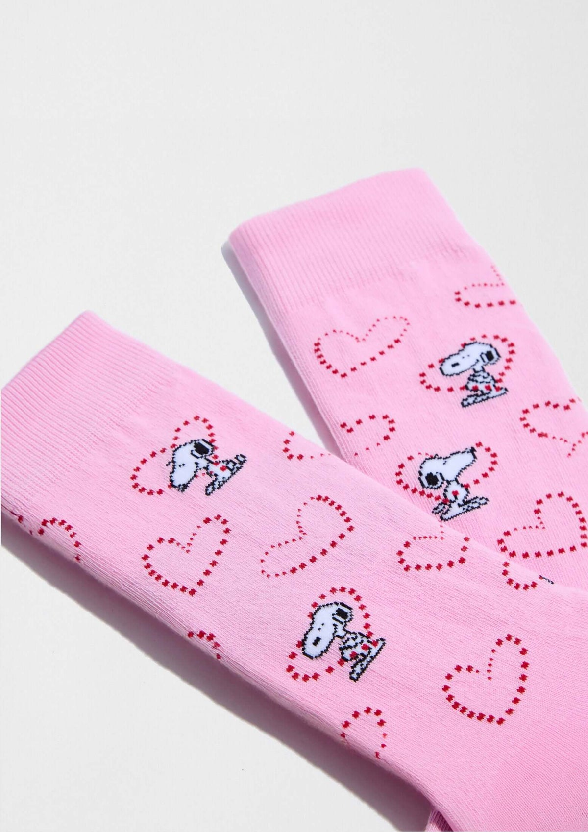 Calcetines altos BeSnoopy Heart Pink de algodón orgánico con dibujos de Snoopy sobre fondo rosa y corazones rojos.