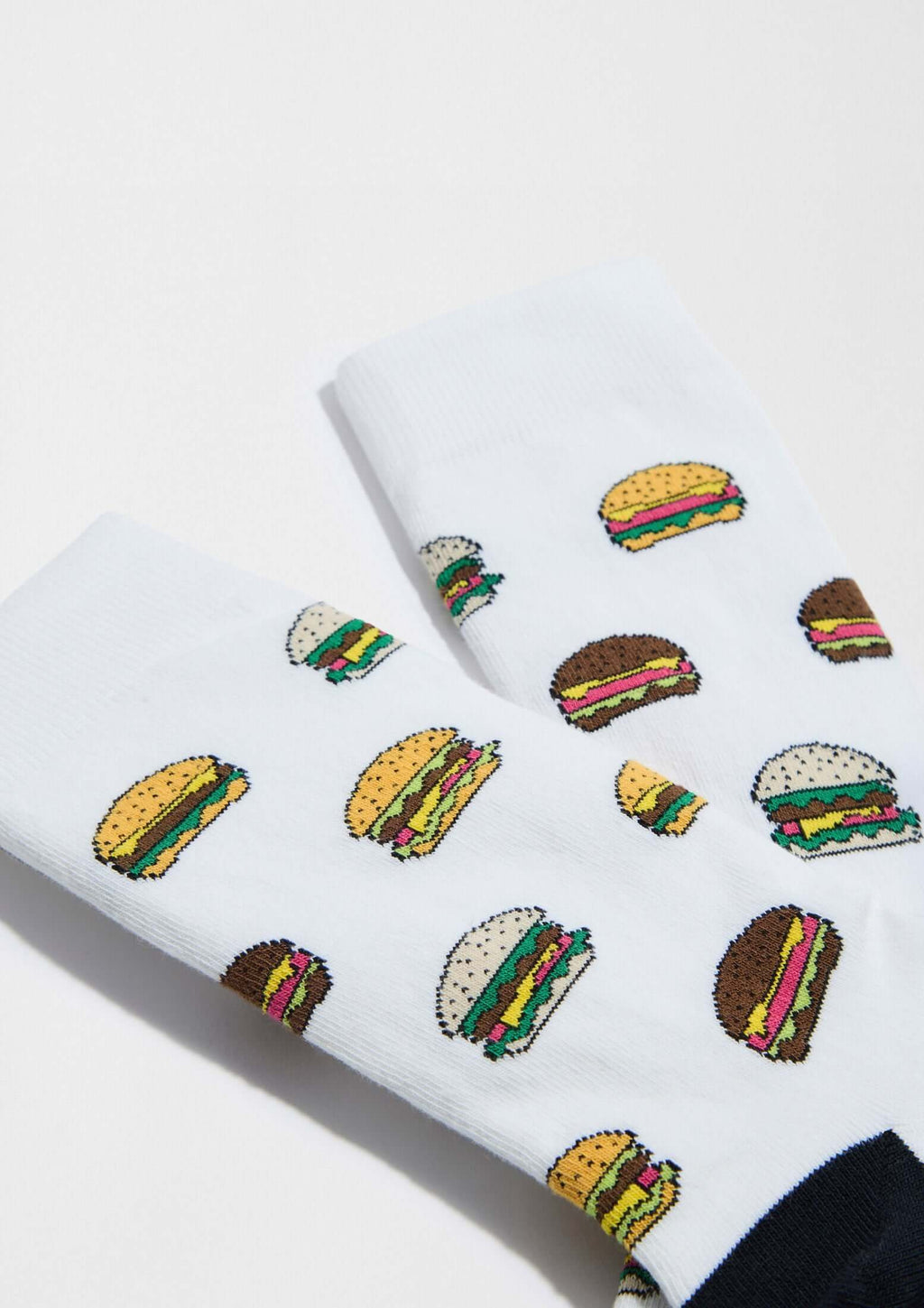 Calcetines BeBurger de fondo blanco con dibujos de hamburguesas en colores variados y detalles en negro.