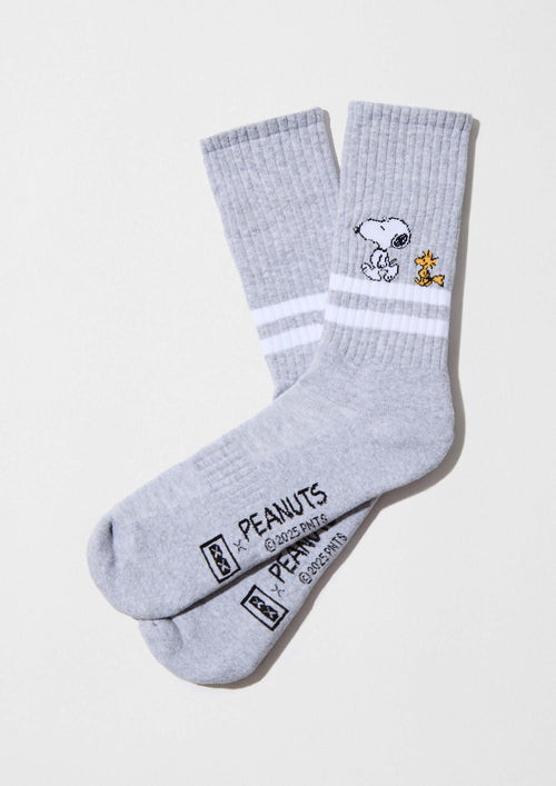 Hombre con calcetines altos de algodón orgánico, BeSnoopy Stripes Grey, sobre fondo claro con dibujos de Snoopy.