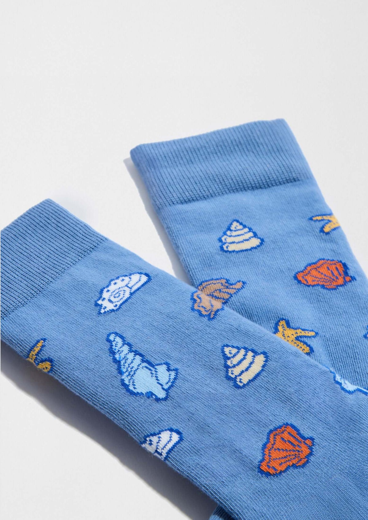 Calcetines BeOcean Blue de algodón orgánico en azul, decorados con conchas marinas en tonos naranja y blanco.