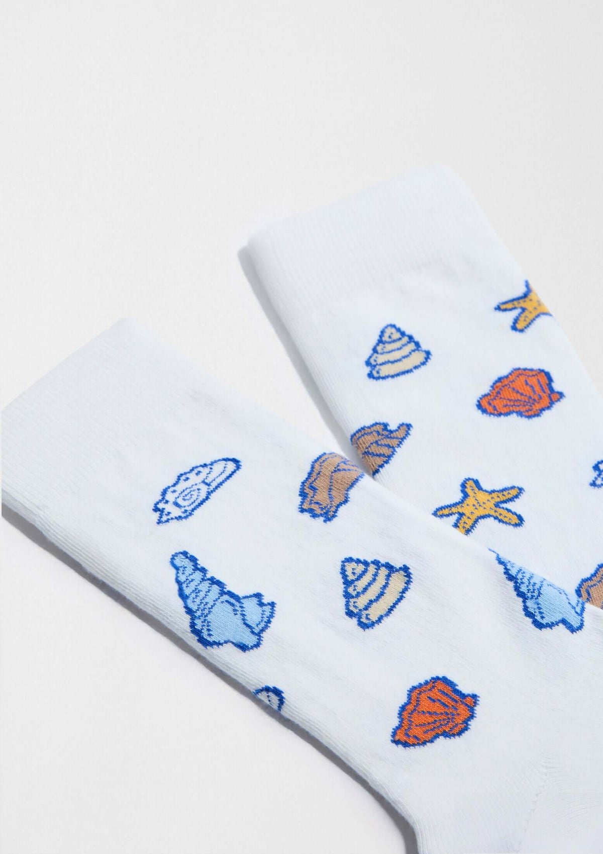 Calcetines BeOcean White en blanco con dibujos de conchas y estrellas de mar en tonos azules y ocres.