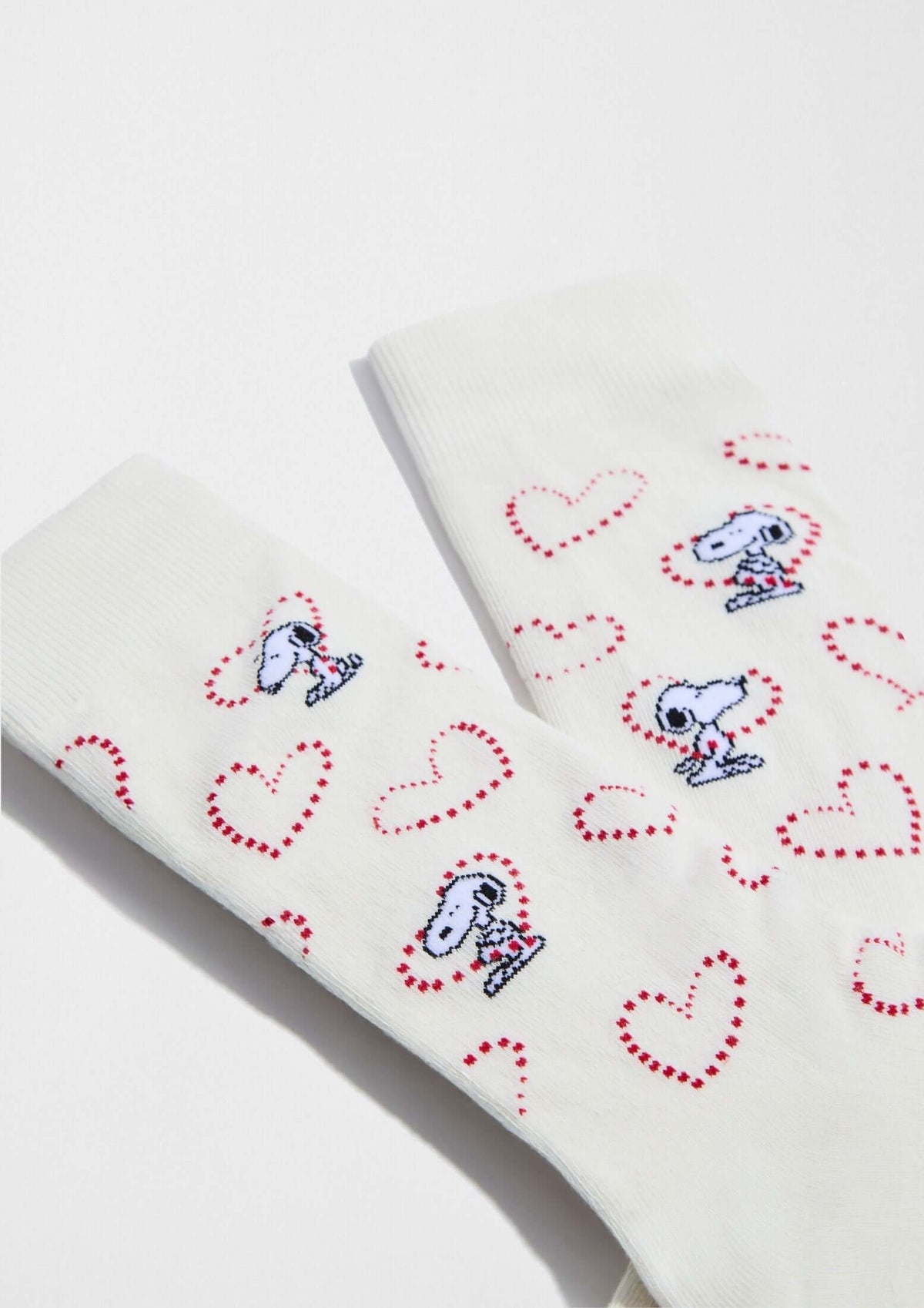 Calcetines altos BeSnoopy Heart Off White de algodón orgánico con dibujos de Snoopy sobre fondo blanco y corazones rojos.