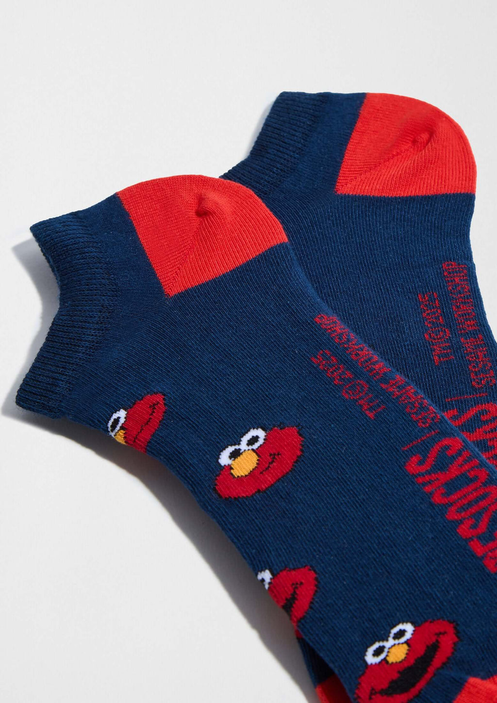 BeSesameStreet Elmo Navy Ankle, calcetines tobilleros con patrón de Elmo en fondo azul marino y talones rojos.