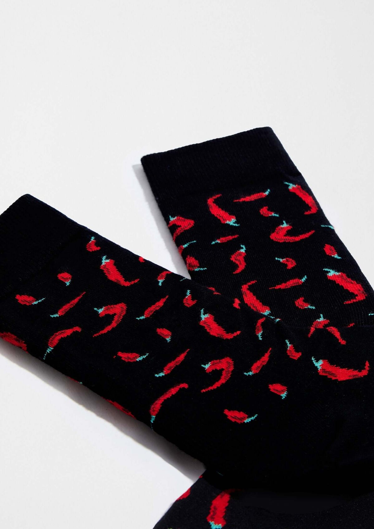Calcetines BeChili Black con dibujos de chiles rojos sobre fondo negro, ideal para un toque divertido.