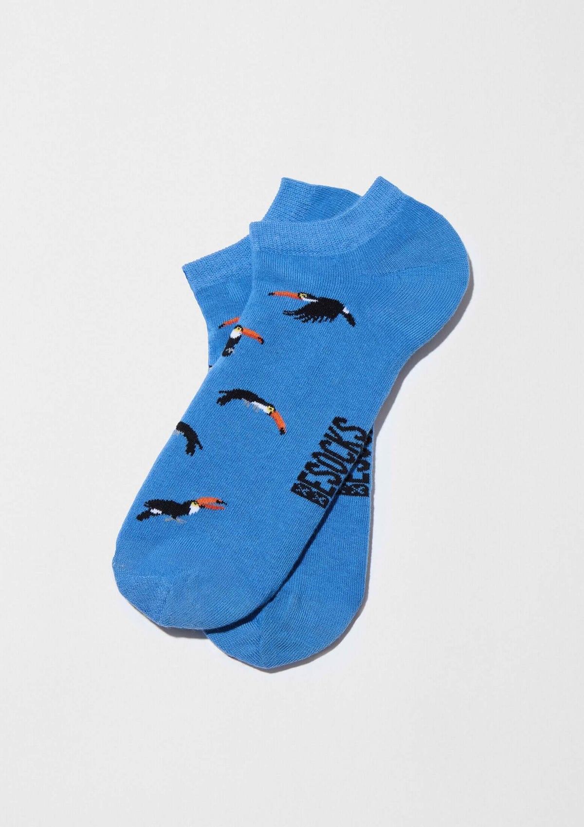 Calcetines tobilleros BeToucan Blue Ankle en azul celeste con tucanes en vuelo y detalles en naranja y negro.