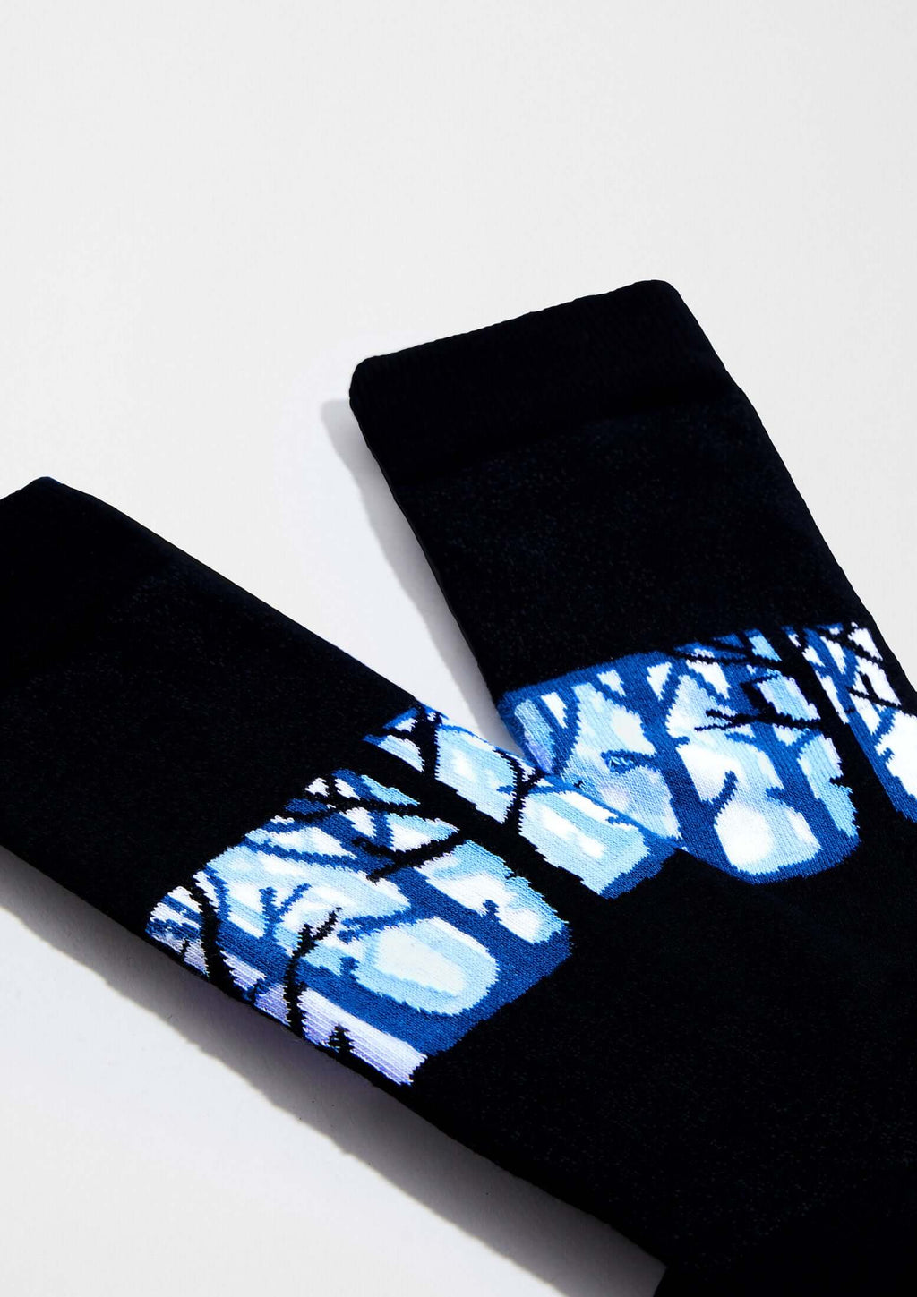 calcetines BeWoods con dibujos de árboles en azul sobre fondo negro, diseño elegante y original.