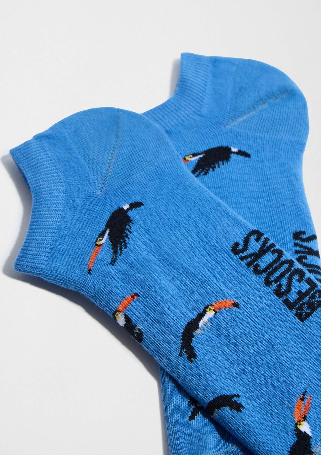 Calcetines tobilleros BeToucan Blue Ankle en azul celeste con patrón de tucanes en vuelo, fabricados en Portugal.