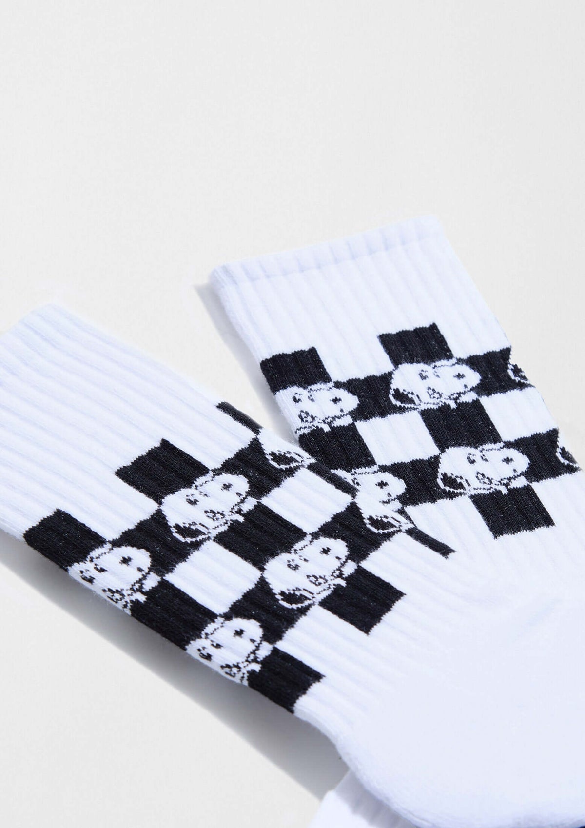 Calcetines altos BeSnoopy Chess en fondo blanco con dibujos de Snoopy sobre patrón de tablero de ajedrez.