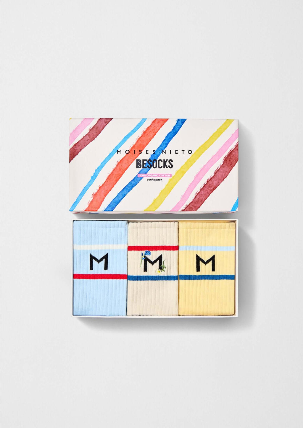 Pack MOISES NIETO x BESOCKS con calcetines de algodón orgánico en azul, amarillo y beige con logo 'M'.