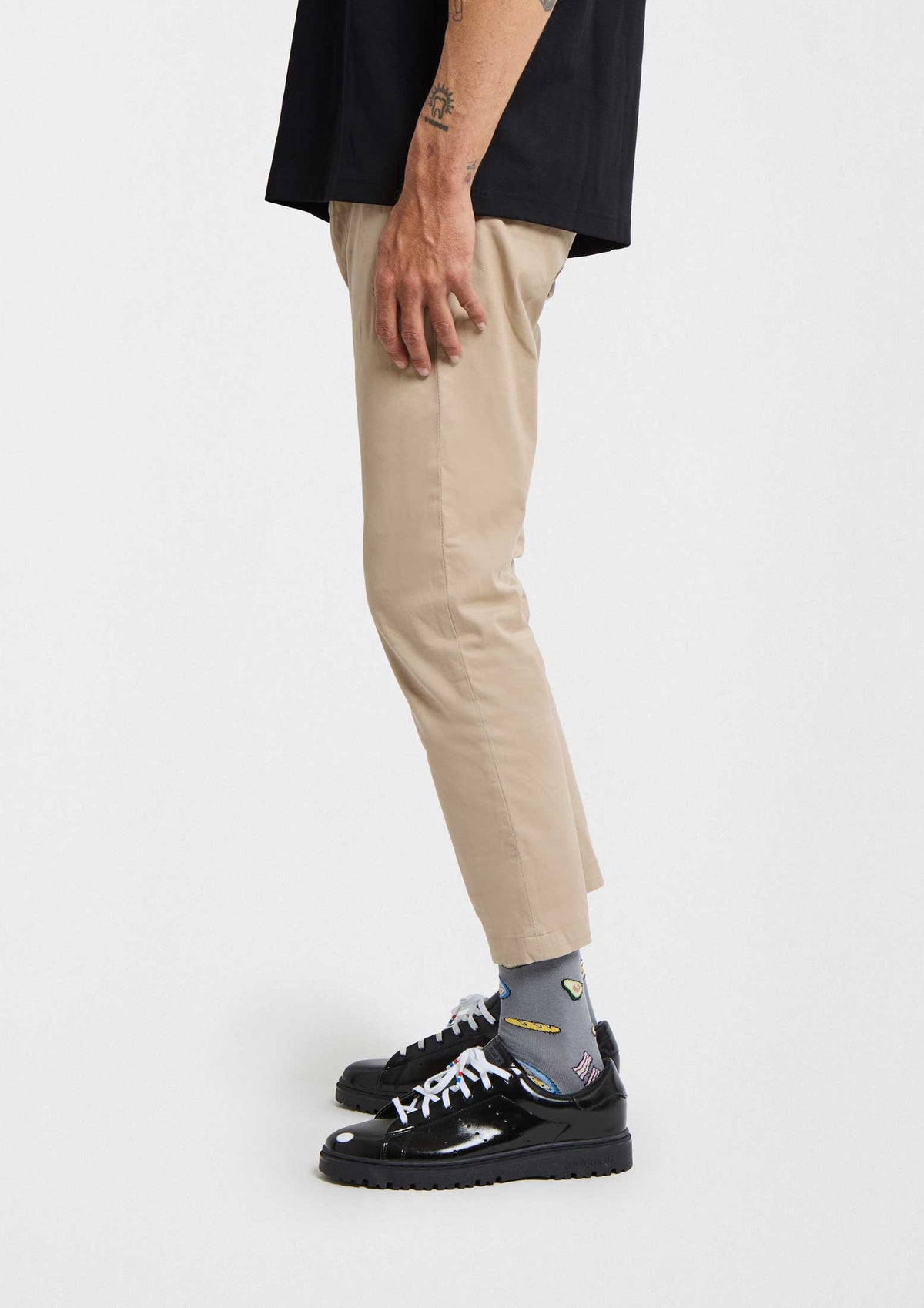 Calcetines BeBrunch Blue en gris con dibujos de comida, pantalones beige y zapatillas negras, estilo casual.
