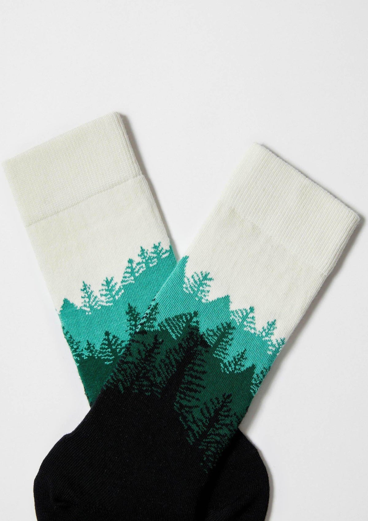 Calcetines BeForest en base negra con diseño de árboles en varios tonos verdes, altura media caña.
