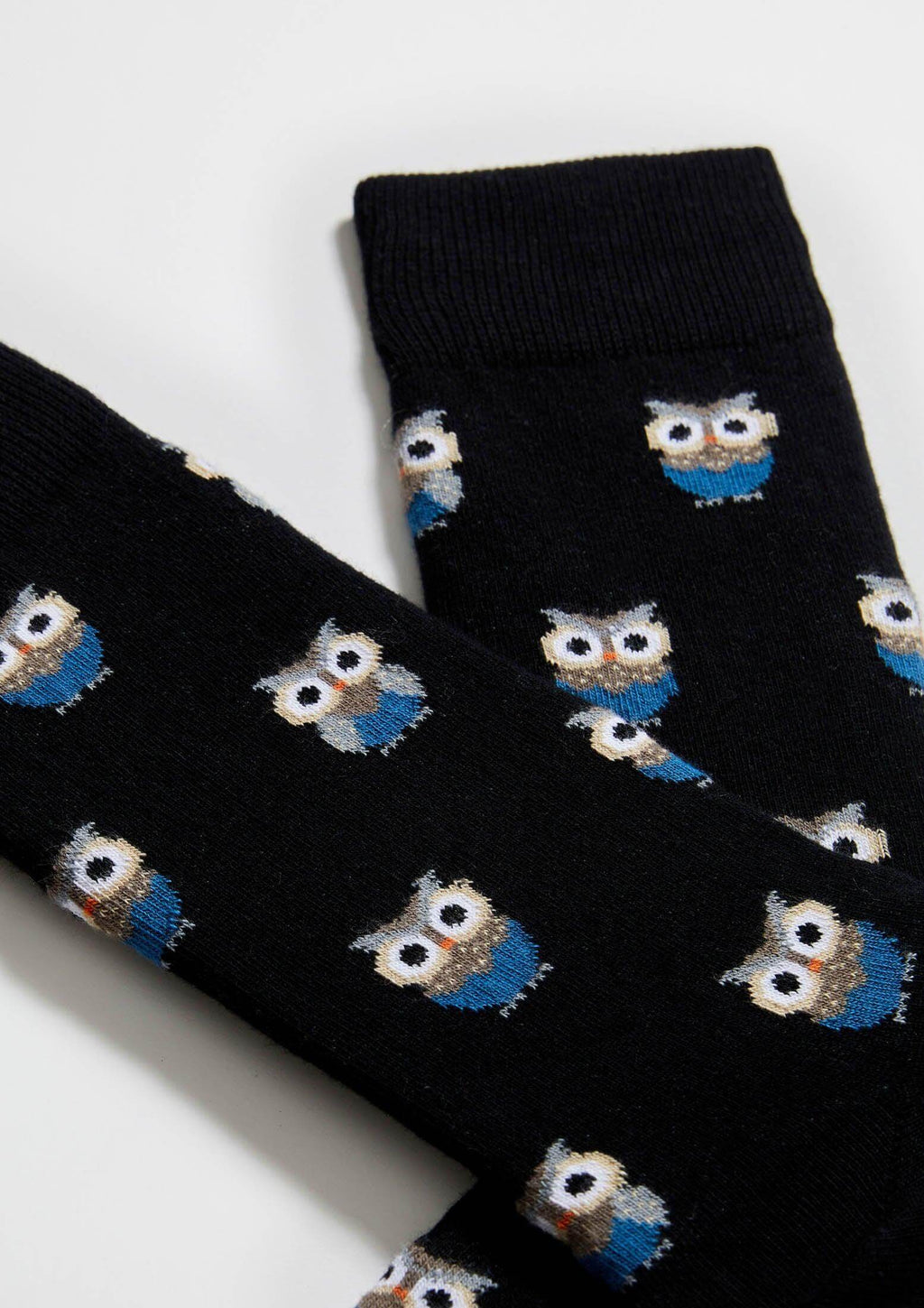 Calcetines BeOwl con fondo negro y búhos en tonos neutros y azul índigo, altura media caña.