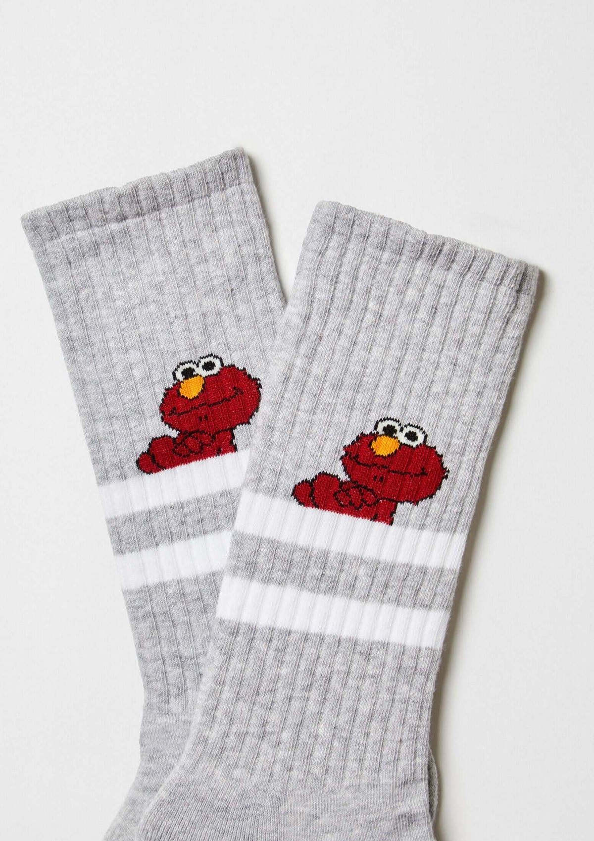 Calcetines BeSesameStreet Elmo Grey en gris con estampado de Elmo y franjas blancas, altura media caña.