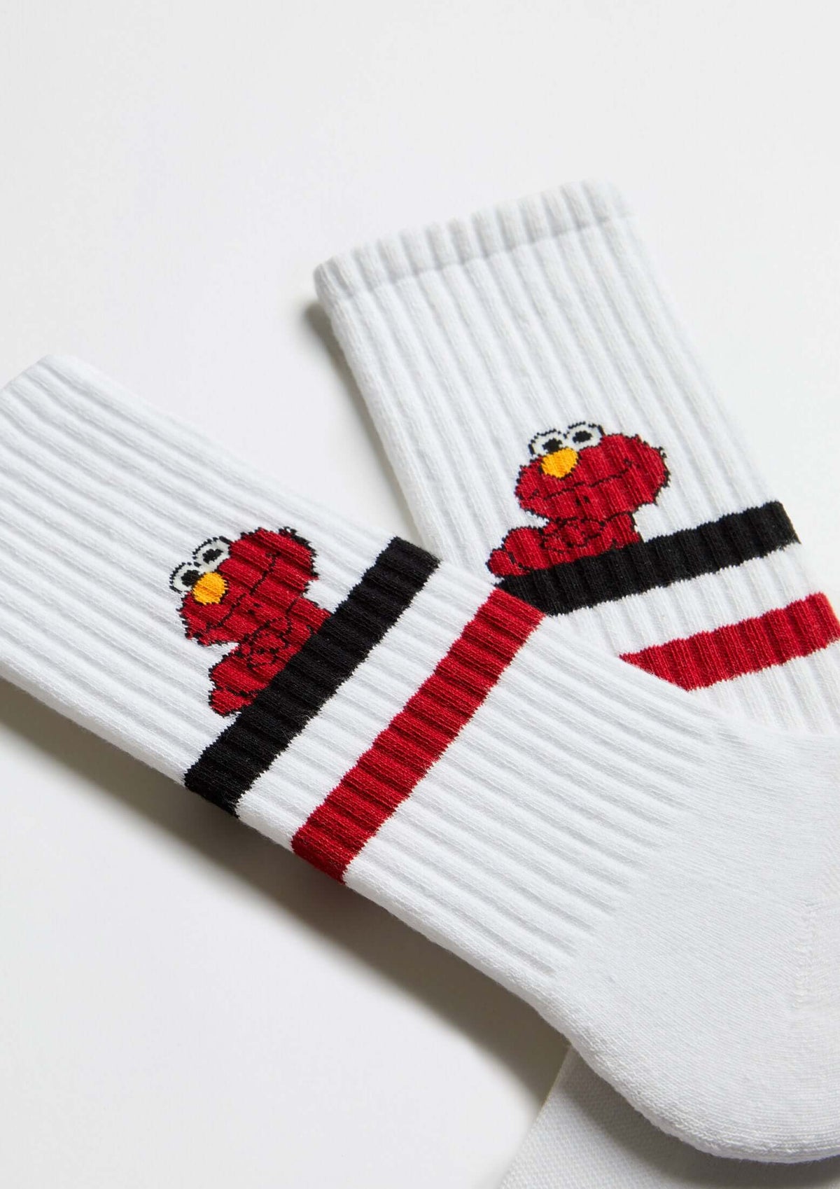 Calcetines BeSesameStreet Elmo White en blanco con franjas negras y rojas, diseño tobillero con Elmo lateral.