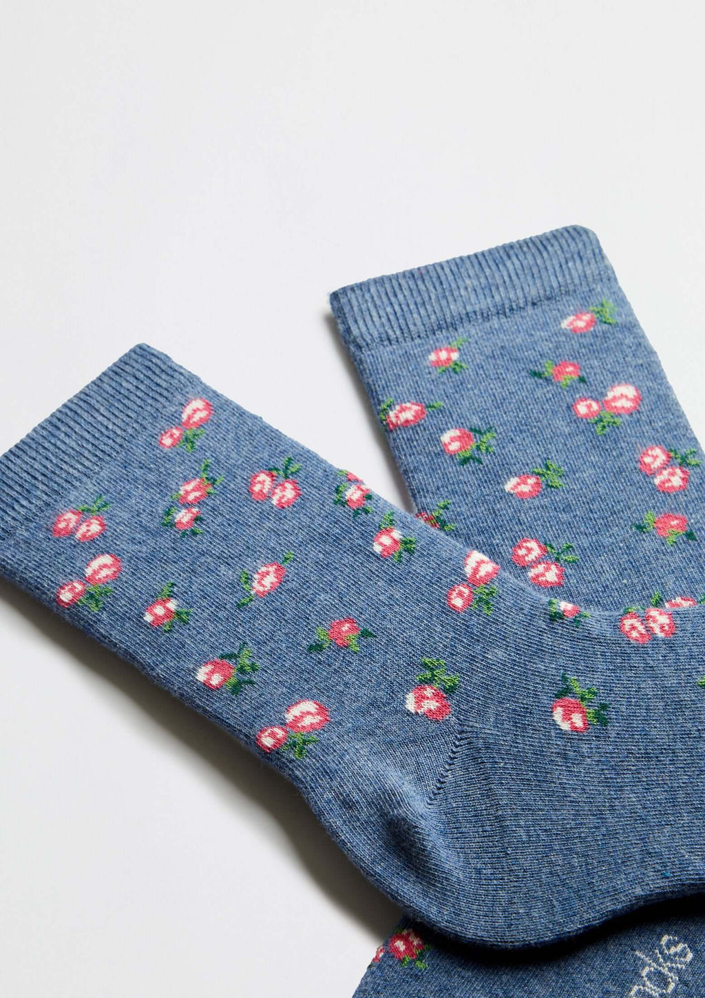 Calcetines BeLiberty Blue de caña baja en fondo azul jaspeado con pequeños dibujos de flores rojas.