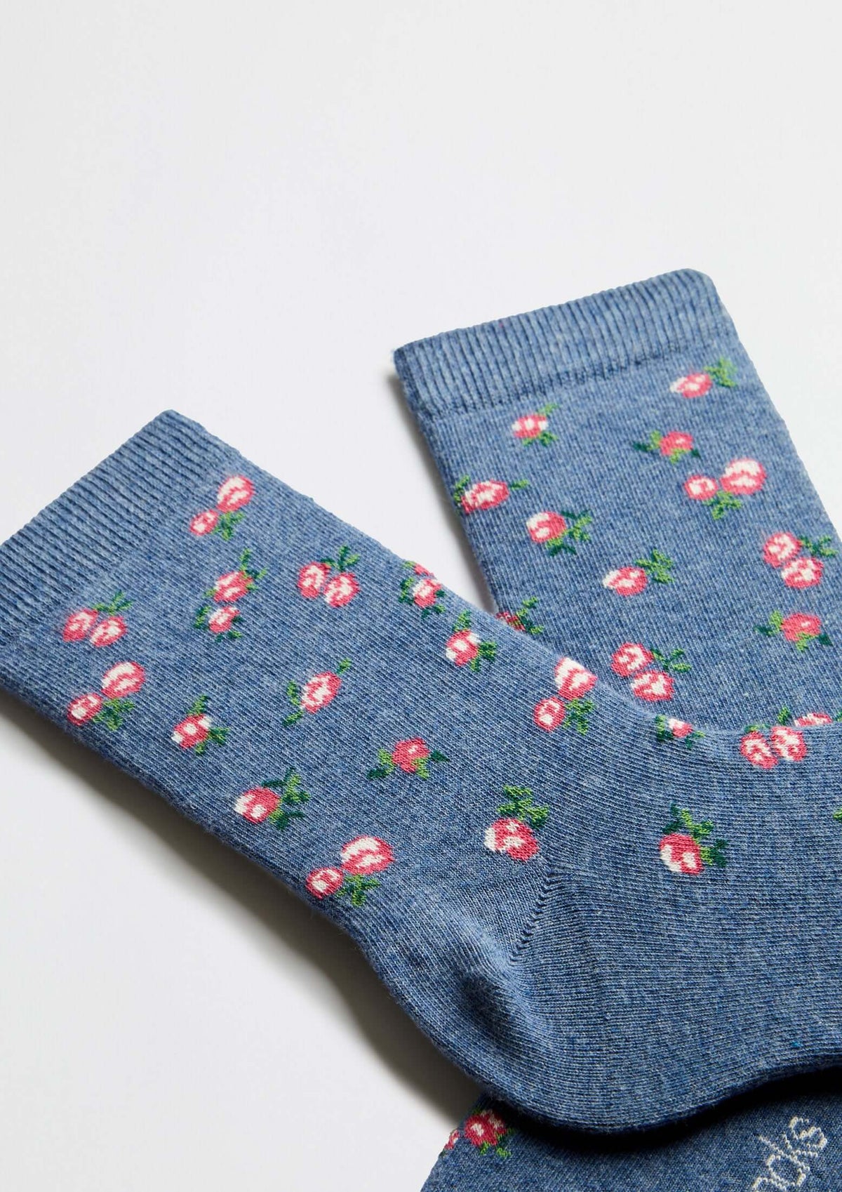Calcetines BeLiberty Blue de caña baja en fondo azul jaspeado con pequeños dibujos de flores rojas.