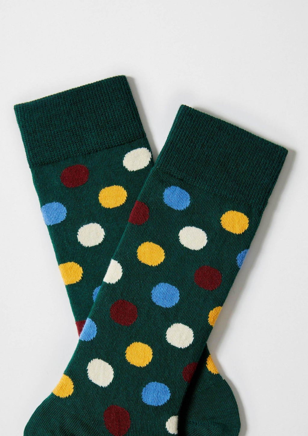Calcetines BePolkadots Multicolor de media caña con puntos grandes en varios colores sobre fondo verde oscuro.