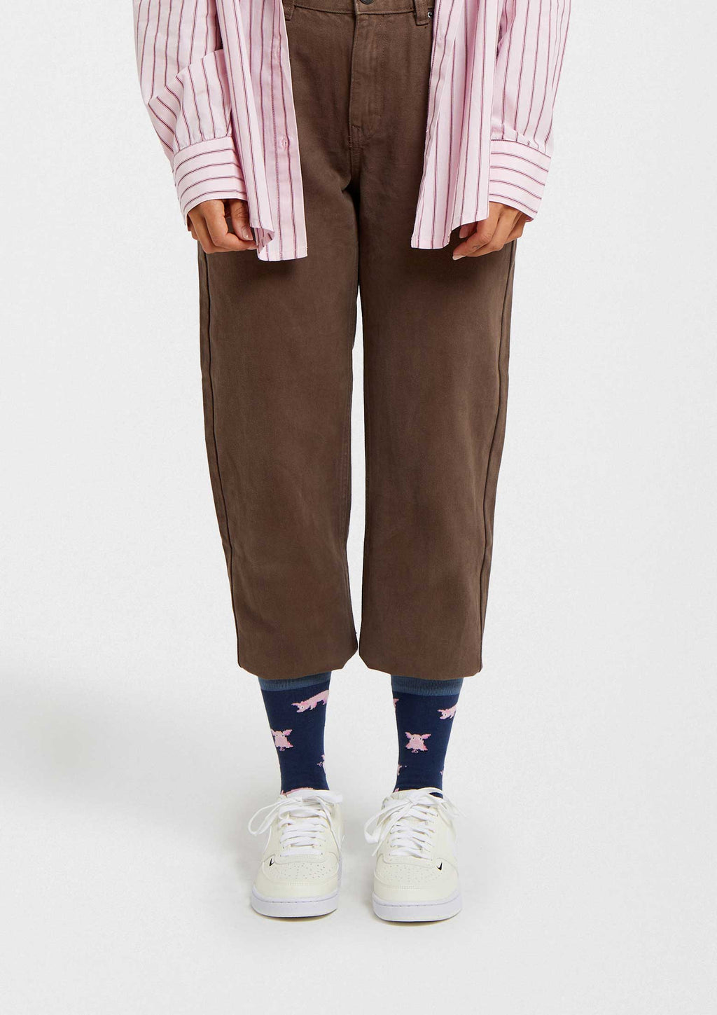 Calcetines BePig en azul marino con dibujos de cerdos rosas, corte a media caña, combinados con pantalones marrones.