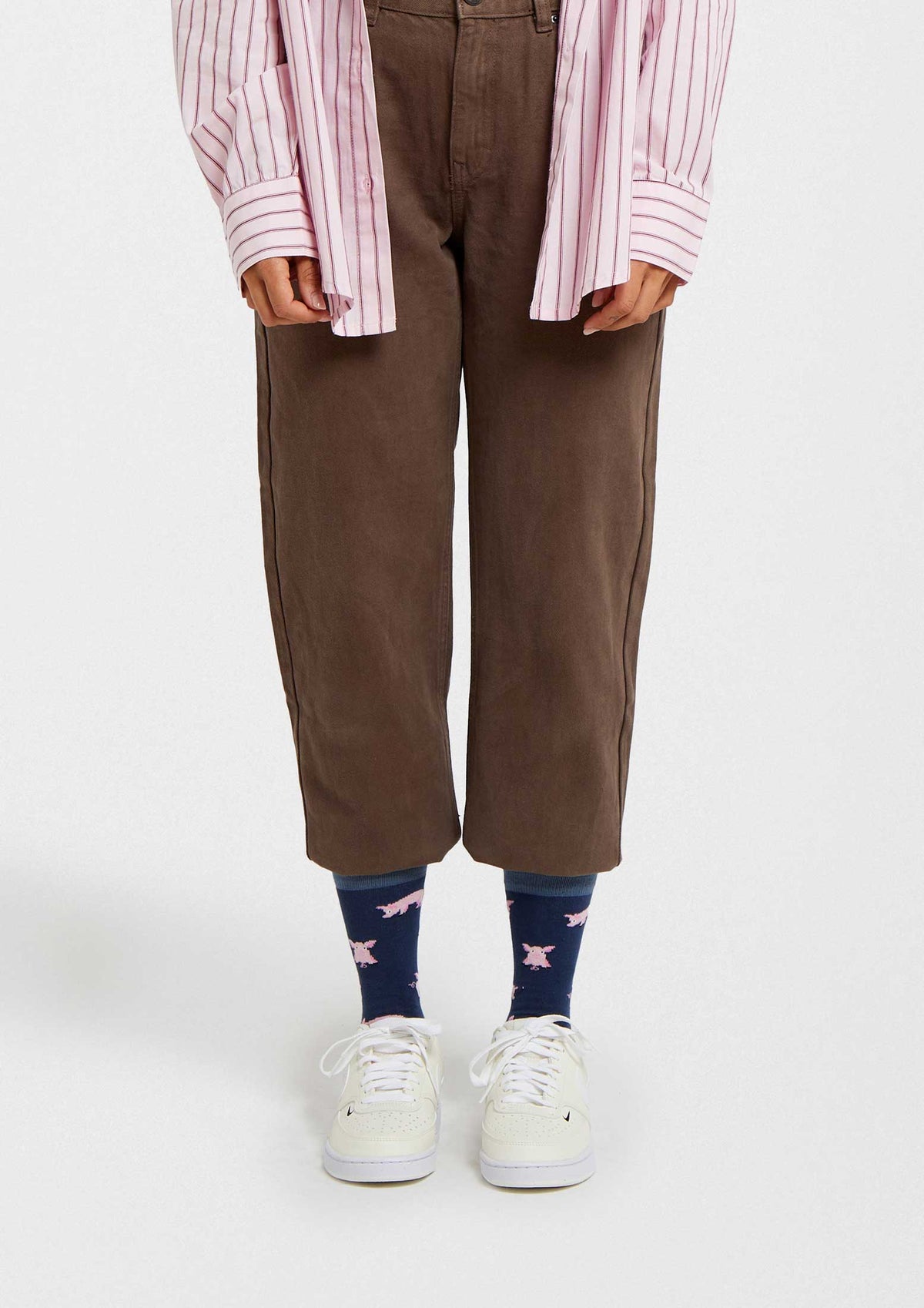 Calcetines BePig en azul marino con dibujos de cerdos rosas, corte a media caña, combinados con pantalones marrones.