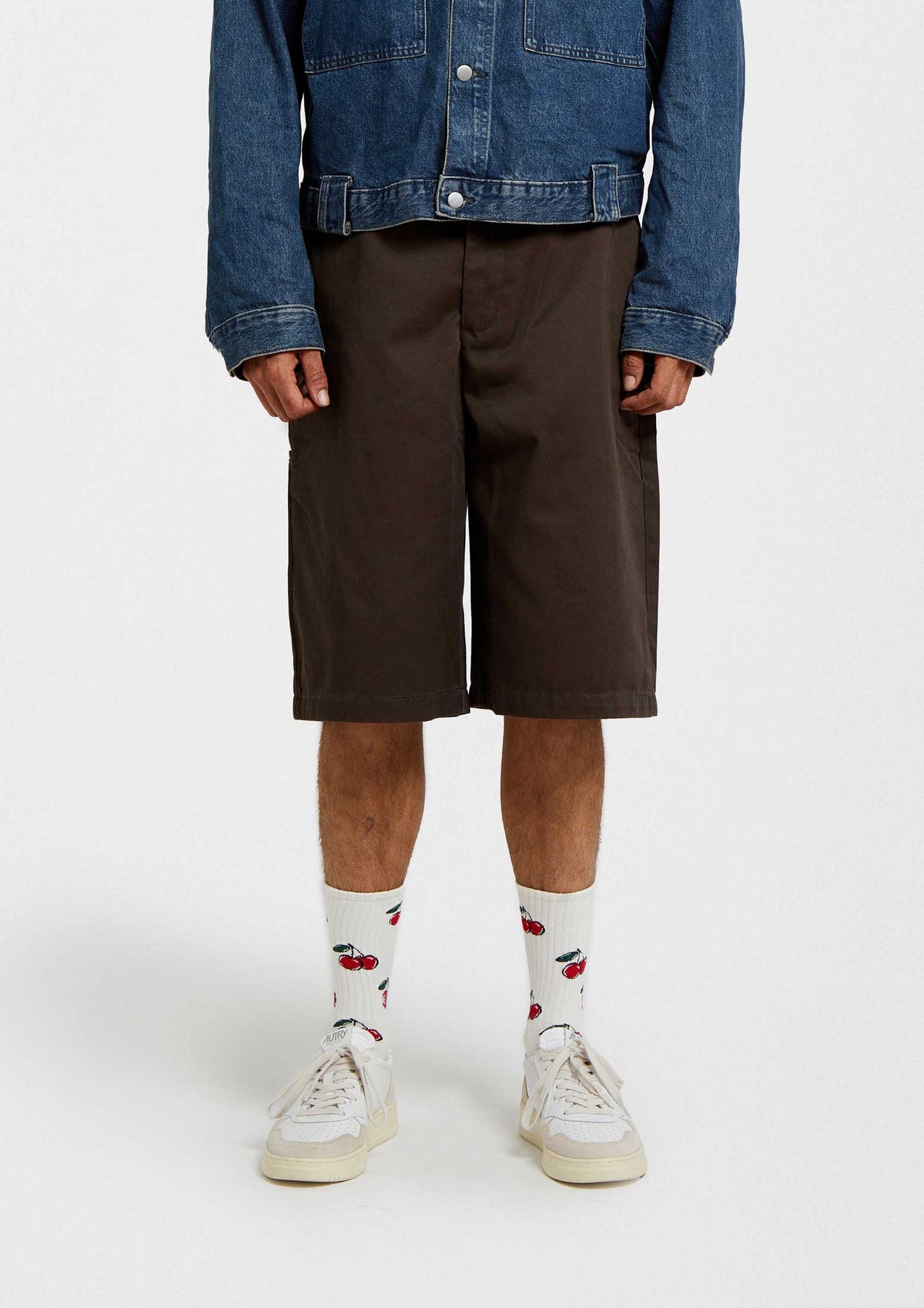Calcetines BeCherry Beige con diseño de cerezas en fondo crudo y altura media caña, combinados con pantalones cortos marrones.