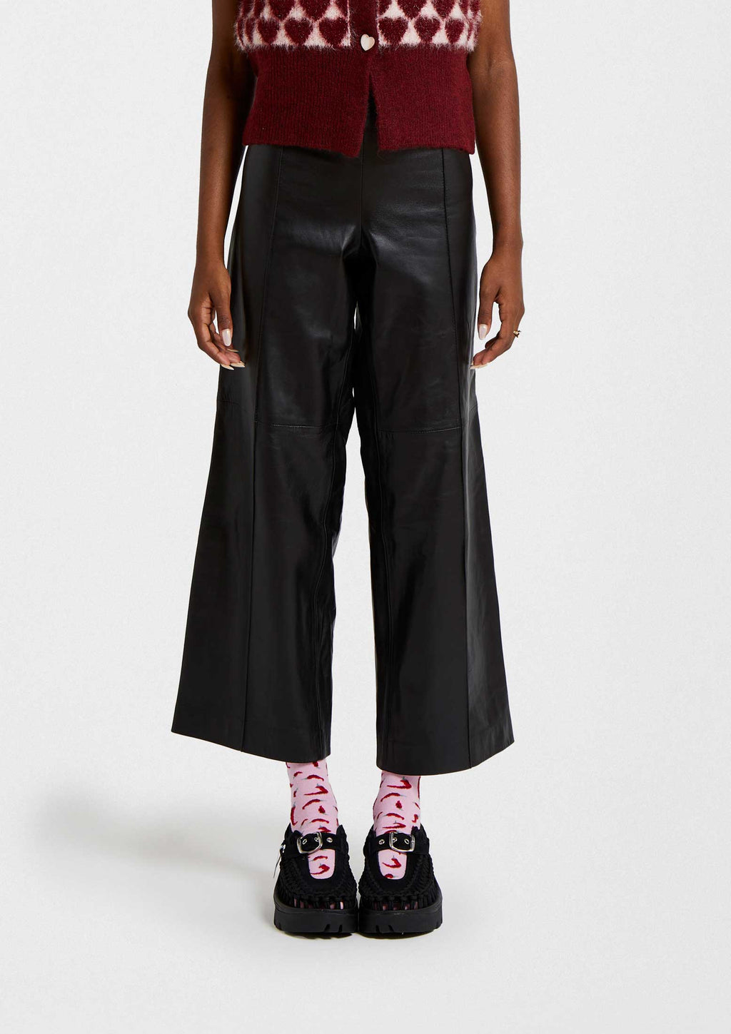 Mujer usando pantalones de cuero negros con calcetines BeChili Pink de dibujos coloridos y zapatos negros.