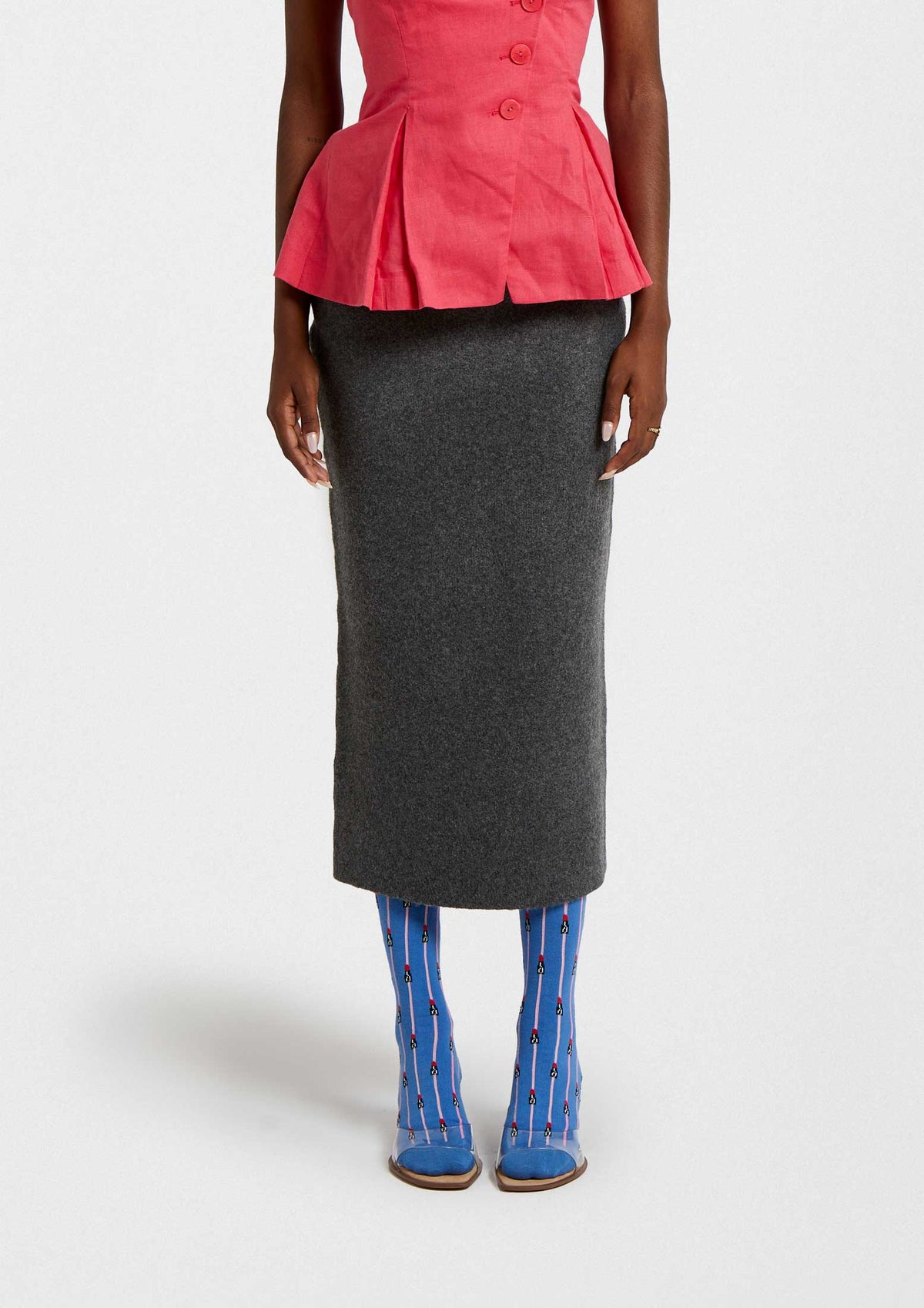 Mujer usando calcetines BeEmilyinParis Lipstick Blue con patrón de labiales, combinados con blusa rosa y falda gris.