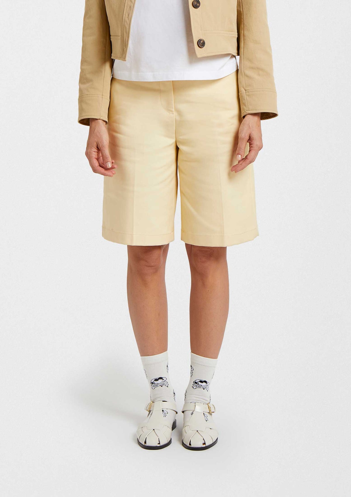 Mujer usando calcetines BeSnoopy Skull Off-White con calaveras sobre base blanca y pantalones cortos color amarillo claro.